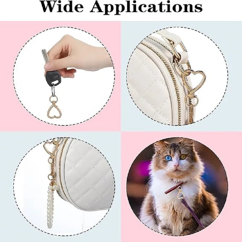 A set of heart-shaped spring hook keychains shown being used on a hand and attached to a leather bag and a cat's collar