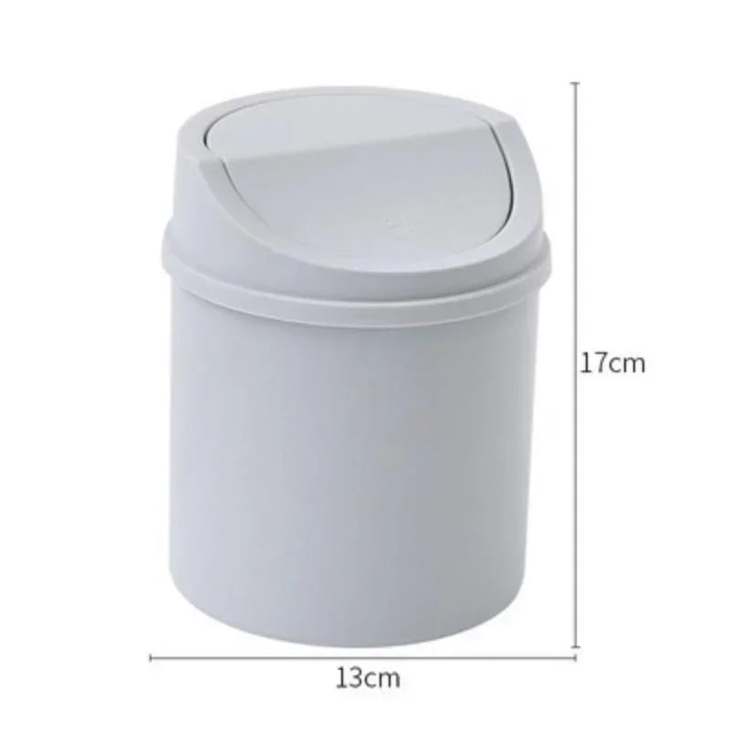 A white compact desktop trash can with a flip-top lid, shown from the side.