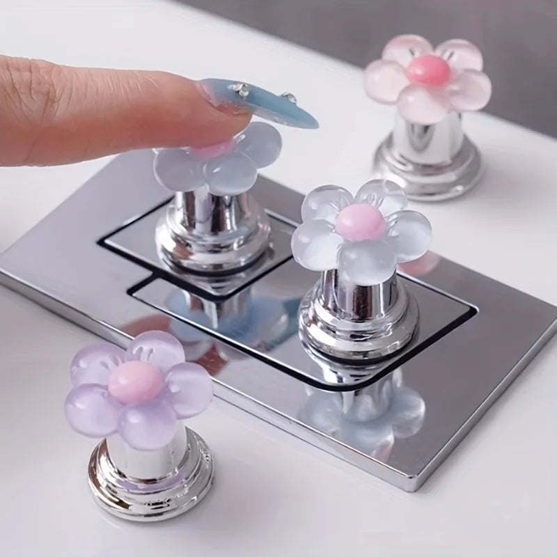 A collection of flower-shaped toilet flush buttons in various pastel colors, including pink and blue, displayed on a silver t