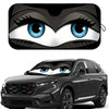 A cartoon eye design featuring blue irises and black fur is placed on a car windshield.