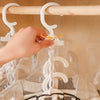 A hand is hanging a white plastic hanger onto a clear vacuum storage bag filled with clothing.