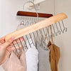 A hand holds a wooden clothes hanger with multiple hooks, used for hanging bras and vests.