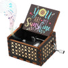 A dark wooden music box with an engraved lid featuring the text You Are My Sunshine and a decorative floral pattern.