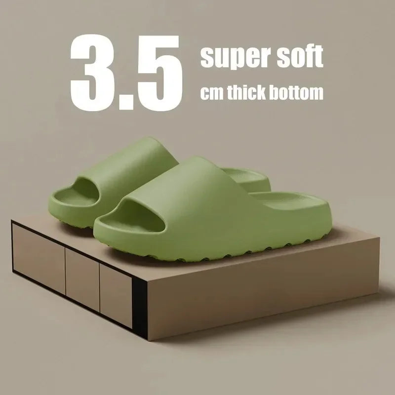 A pair of light green EVA slides with a 3.5 cm thick bottom resting on a brown wooden surface.