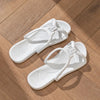 Une paire de tongs pliables blanches en EVA posées sur une surface en bois.