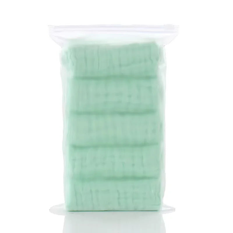 Paquete de plástico transparente con un pack de 5 toallitas orgánicas de algodón para bebé y cara de color verde claro.