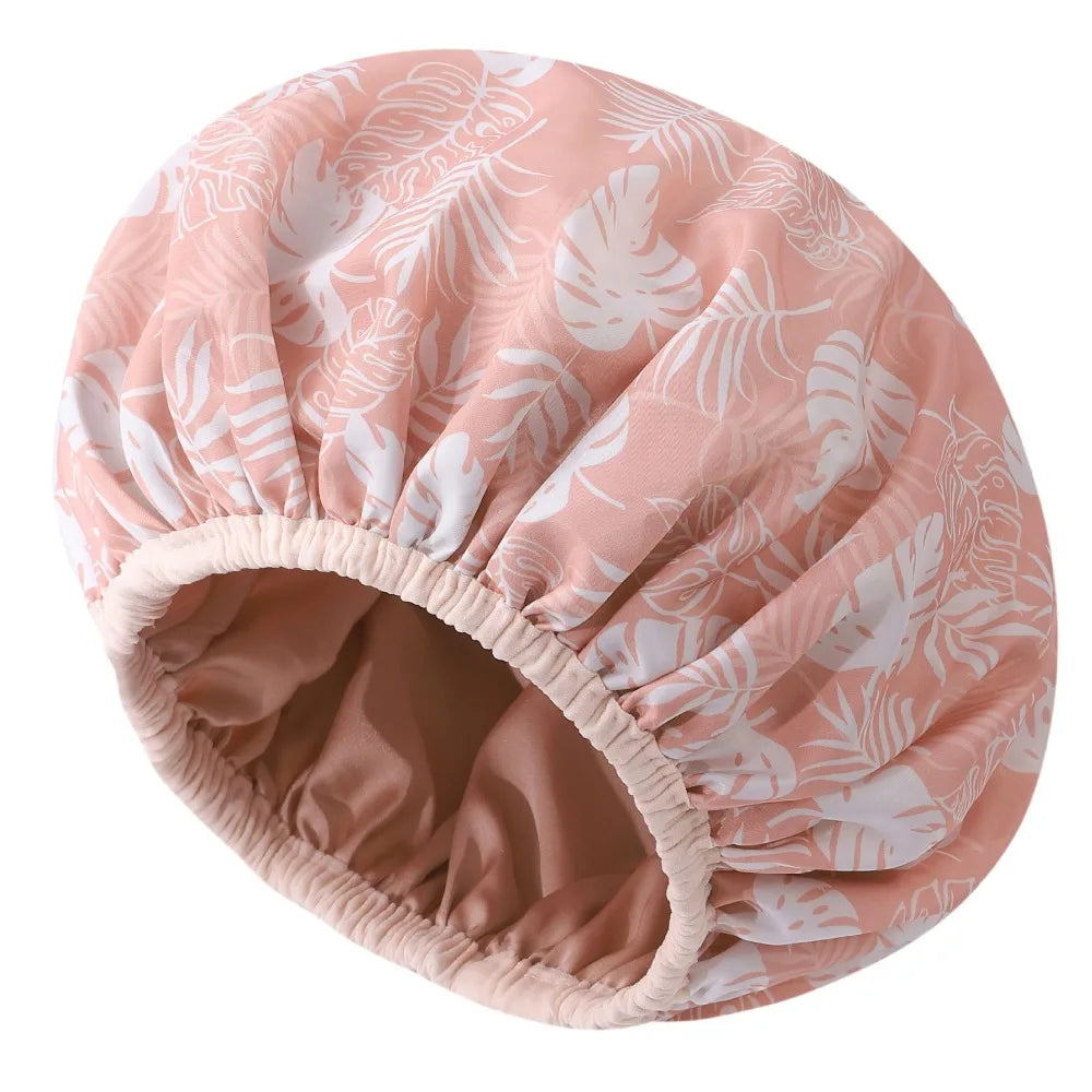 A pink and white floral patterned reusable satin lined shower cap.