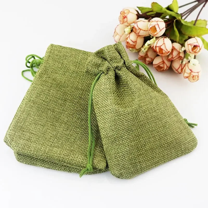 Natürige grüne Jute-Geschenktasche mit Schnur, neben einer Ansammlung von orange-weißen Blumen.