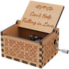 A vintage engraved wooden music box with a lid showing the text Can't Help Falling in Love