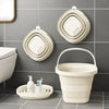 A white collapsible water bucket with a handle is displayed on a gray tiled wall next to various bathroom accessories.