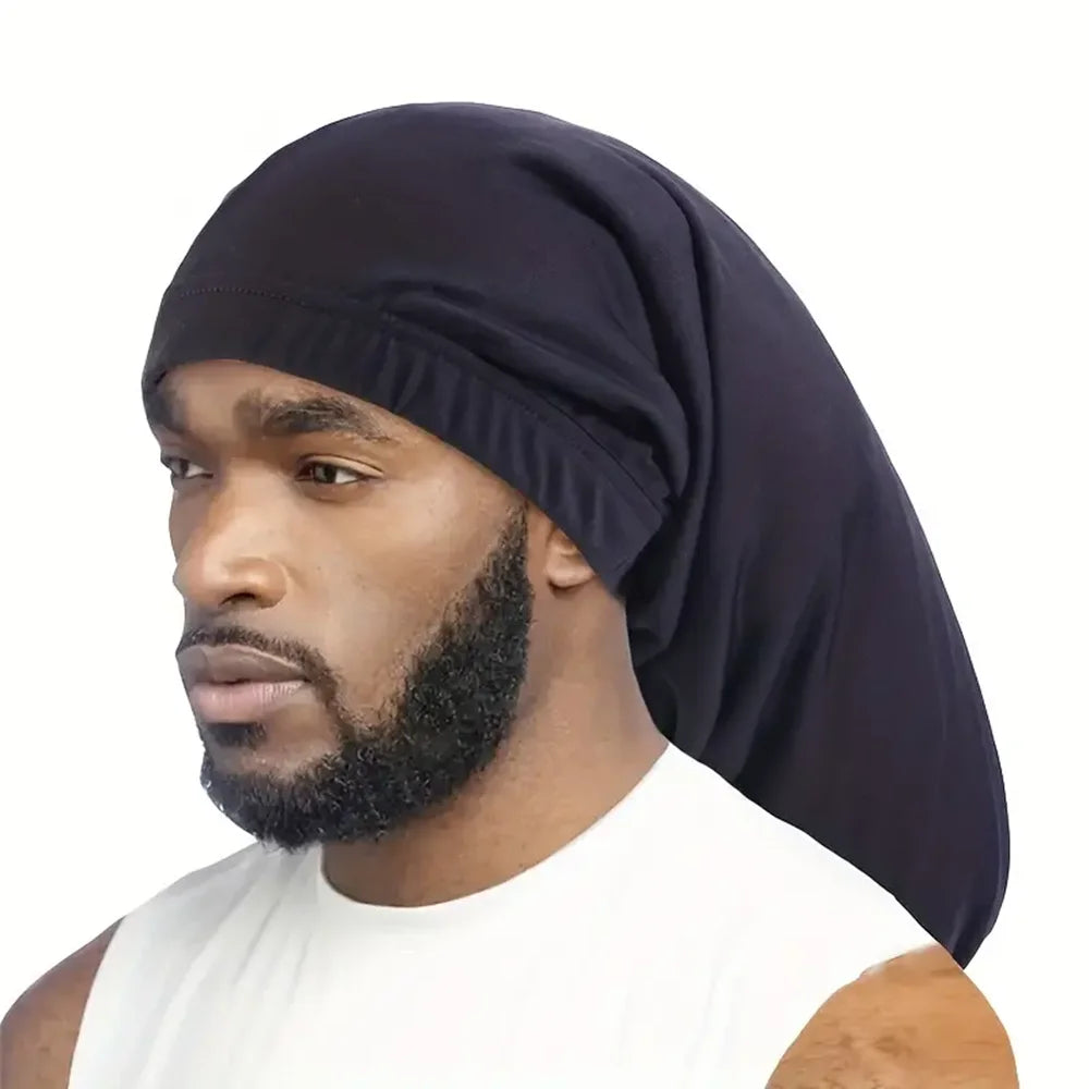 A man wearing a black satin hair bonnet with a beard, looking to the side.