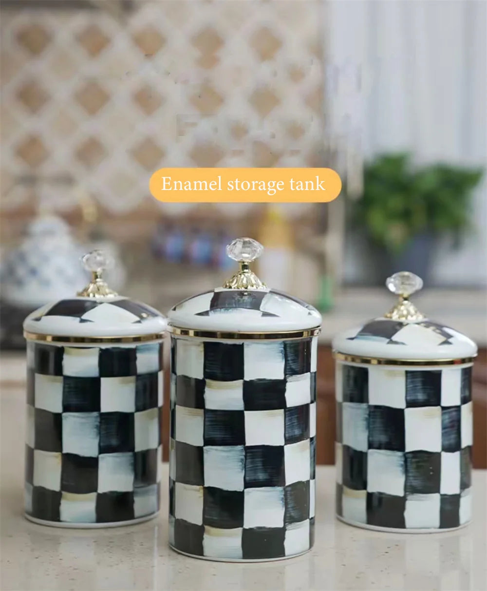 Three black and white checkered enamel storage jars with gold lids on a light surface.