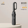 A black obsidian folding umbrella with a handle, shown standing on a light surface.