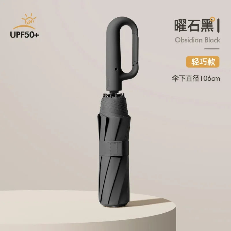A black obsidian folding umbrella with a handle, shown standing on a light surface.