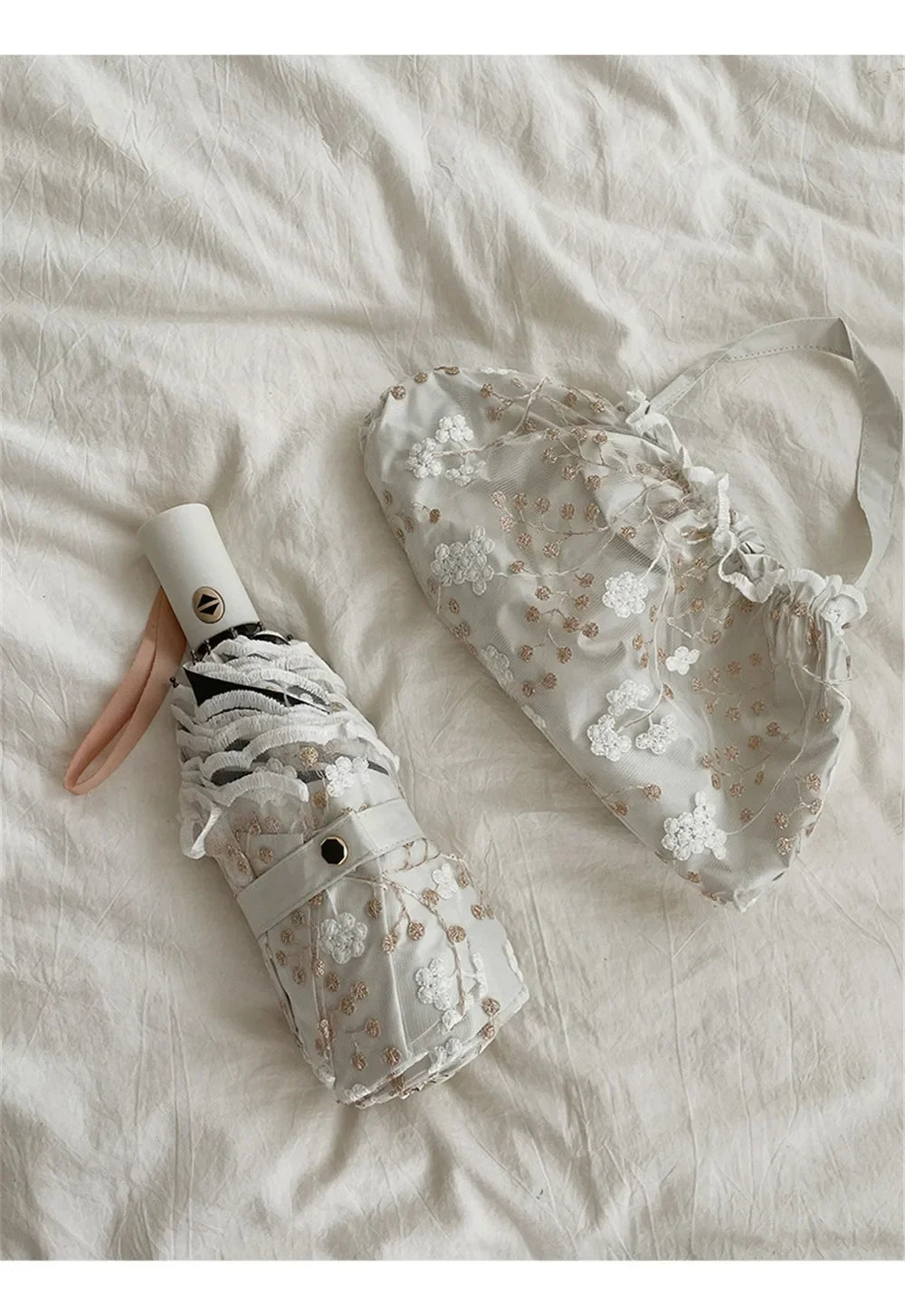 A white full-automatic embroidered sun umbrella is shown lying on a white sheet.