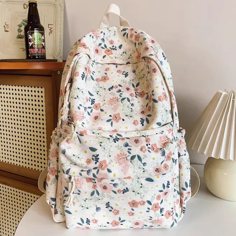 A floral print backpack set featuring a white background with pink and green flowers, shown on a white surface.