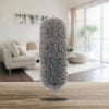 A fluffy gray extendable microfiber duster standing upright on a wooden surface.