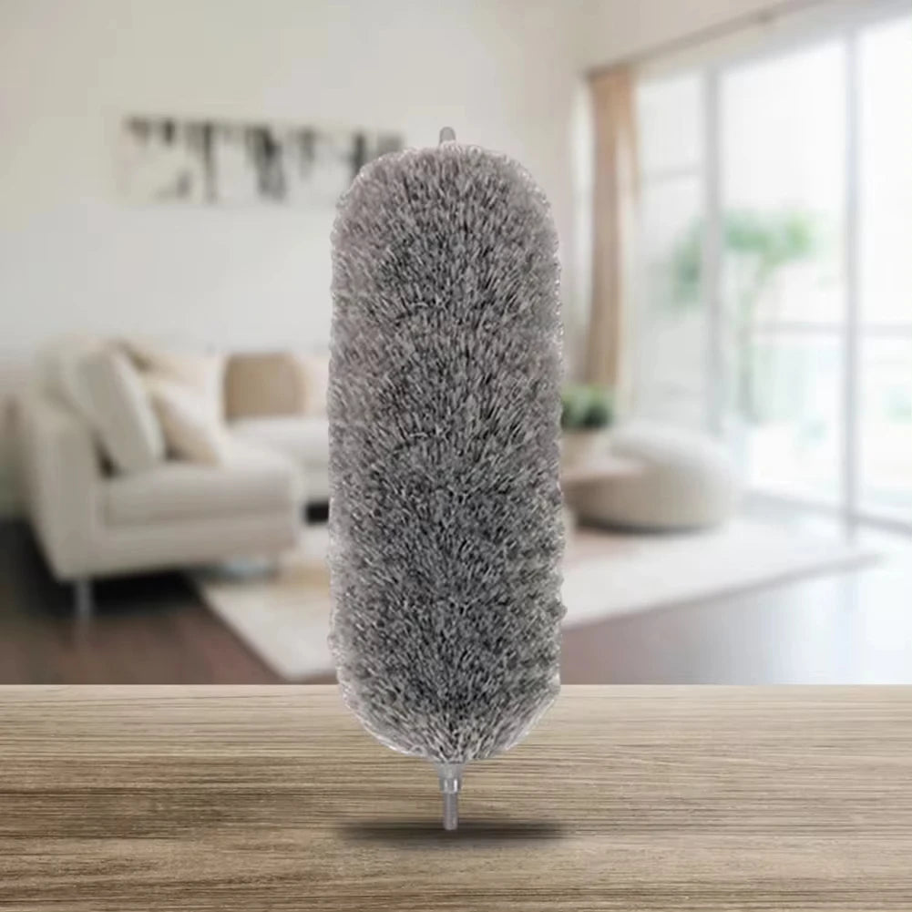 A fluffy gray extendable microfiber duster standing upright on a wooden surface.