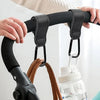 Hands are attaching or adjusting universal stroller hook carabiner accessories to a stroller handlebar.
