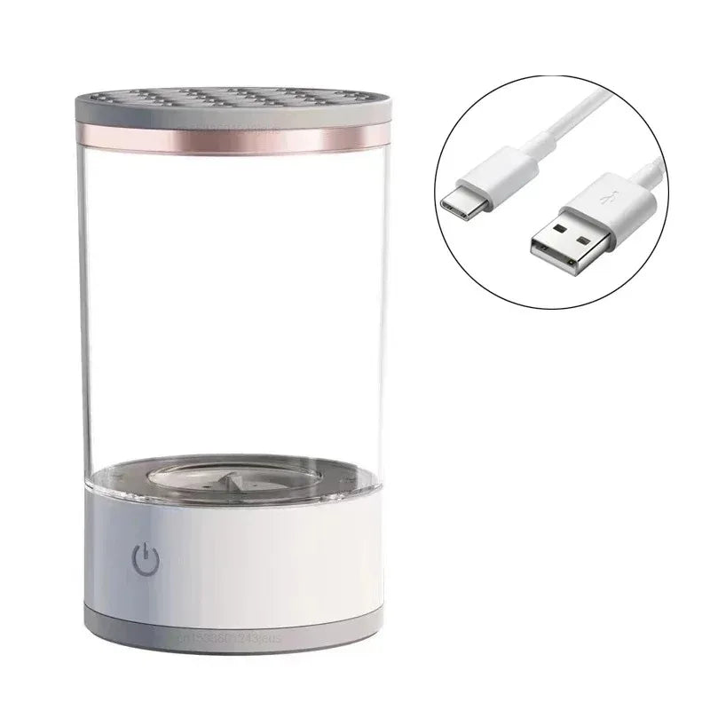 A clear glass electric makeup brush cleaner with a white base and a power cord shown in detail.