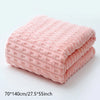 A stack of pink coral velvet bath towels folded neatly on a white surface.