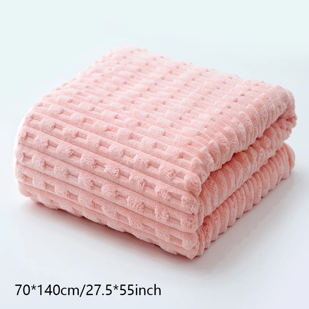 A stack of pink coral velvet bath towels folded neatly on a white surface.