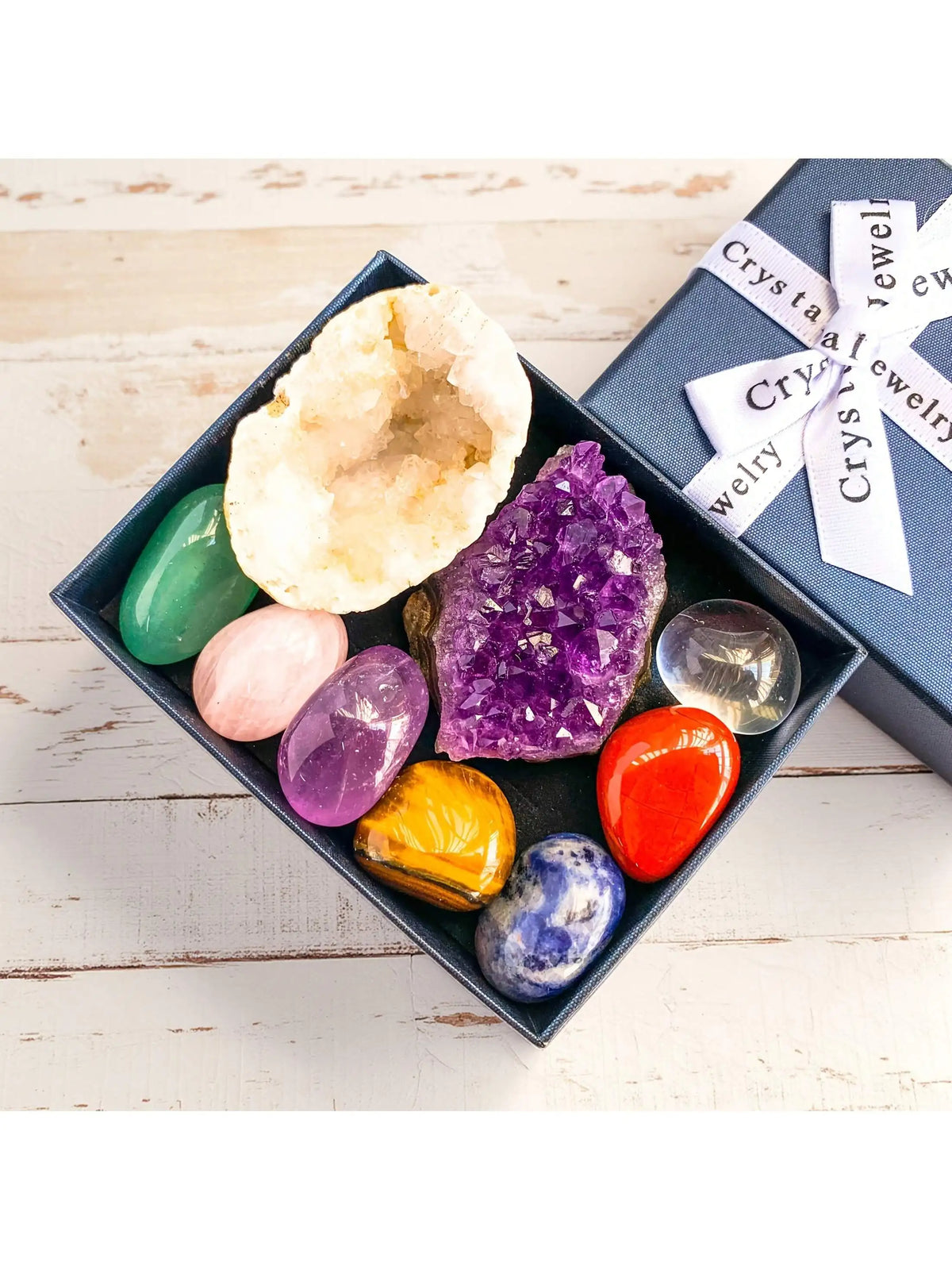 A dark tray holds various natural crystal stones including quartz, jade, amethyst, and citrine for meditation and decor.