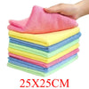 A hand is holding a stack of pink, yellow, and blue reusable microfiber cleaning cloths.