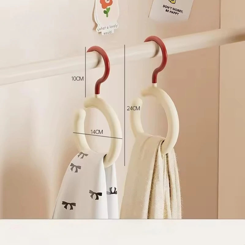 Un cintre blanc avec un crochet incurvé et un cintre rond est exposé sur une étagère.