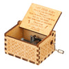 A vintage engraved wooden music box with a lid open, showing an inscription inside.
