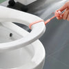 A hand is using a silicone ring opener to lift or open the lid of a white toilet seat.