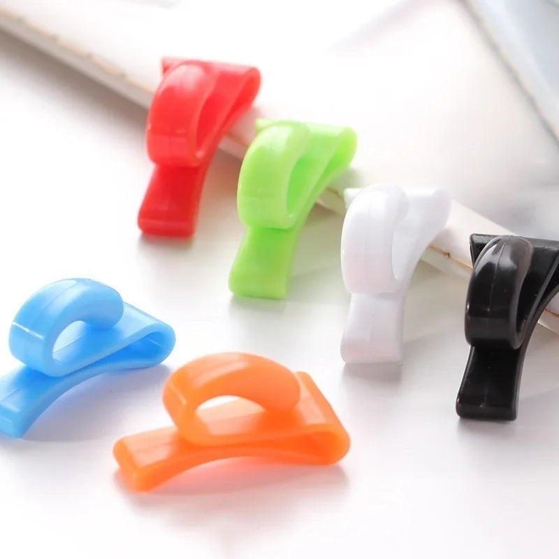 A collection of four colorful key holder clips in red, green, white, and black arranged on a white surface.