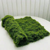 A vibrant green artificial moss garland spread out on a white surface.