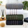 A stack of coral fleece towels in various shades of gray, green, and navy blue with gold stripes.