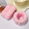 A set of pink microfiber wrist sweatbands for face washing and skincare placed on a white surface.