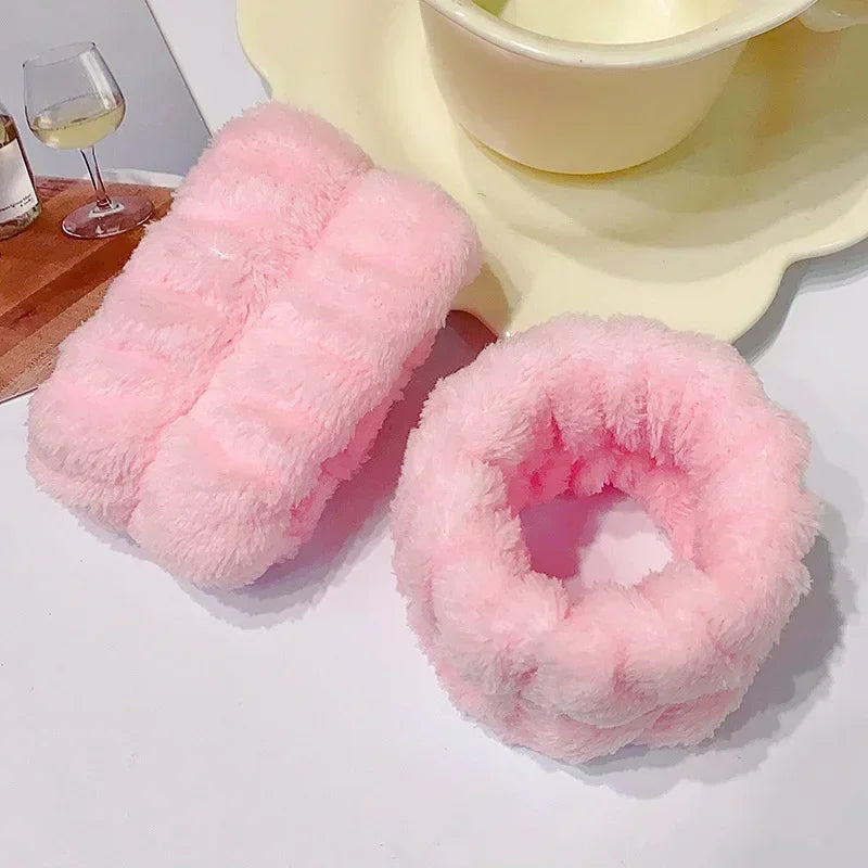 A set of pink microfiber wrist sweatbands for face washing and skincare placed on a white surface.