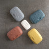 A collection of five portable travel soap boxes in various colors including gray, blue, white, pink, and yellow, arranged on 