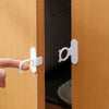 A hand is using a white silicone self-adhesive cabinet door handle lifter to open a wooden cabinet door.