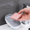 A hand places a pink silicone anti-slip strip onto a white soap dish with a suction cup base.