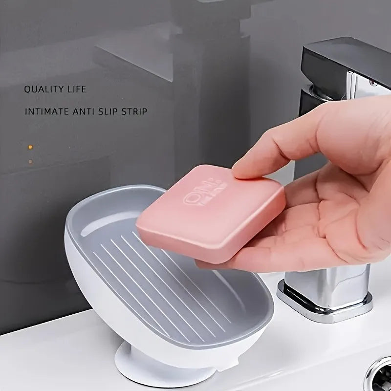 A hand places a pink silicone anti-slip strip onto a white soap dish with a suction cup base.