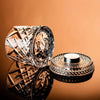 Un par de elegantes vasos de whisky facetados y una base decorativa a juego, exhibidos sobre una superficie marrón.