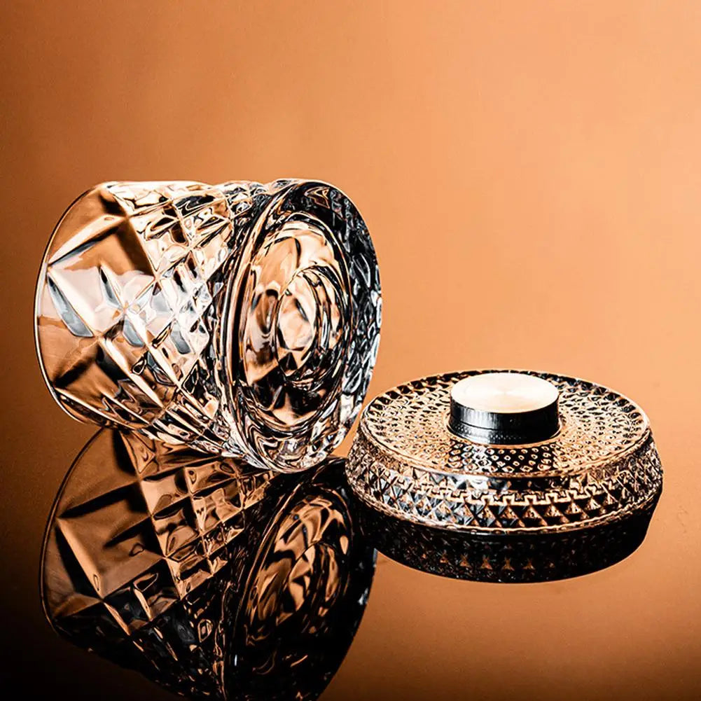 Un par de elegantes vasos de whisky facetados y una base decorativa a juego, exhibidos sobre una superficie marrón.