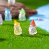 A collection of luminous resin mini fairy gnomes in various pastel colors resting on green grass.
