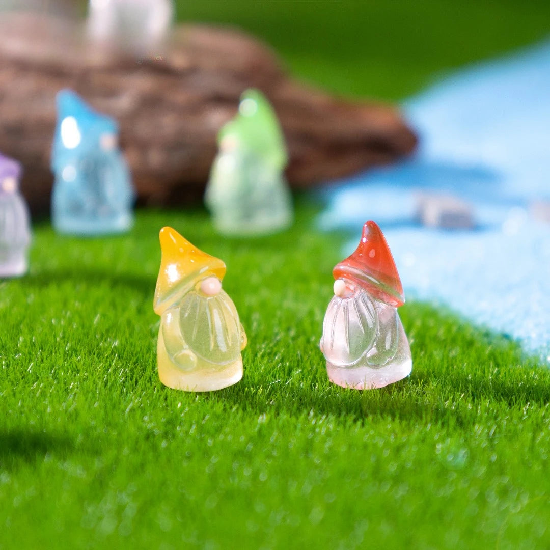 A collection of luminous resin mini fairy gnomes in various pastel colors resting on green grass.