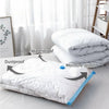 White vacuum storage bags with hand pump for clothes and blankets shown on a bed.