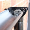 Nahaufnahme eines Metall-Aluminium-Rinnenblatt-Schmutzfilters, der in eine Rinne eingeführt wird.