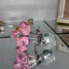Skulptur einer Kristallrose mit rosa und klaren facettierten Kristallen, auf einer Glasoberfläche