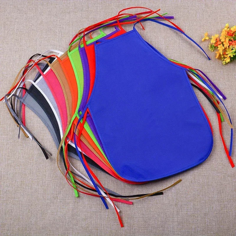 A colorful pack of thirty non-woven craft aprons in various bright colors laid out on a beige fabric background.