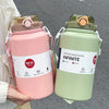 A pink insulated stainless steel water bottle with a lid and straw is held by a person, next to a green one.