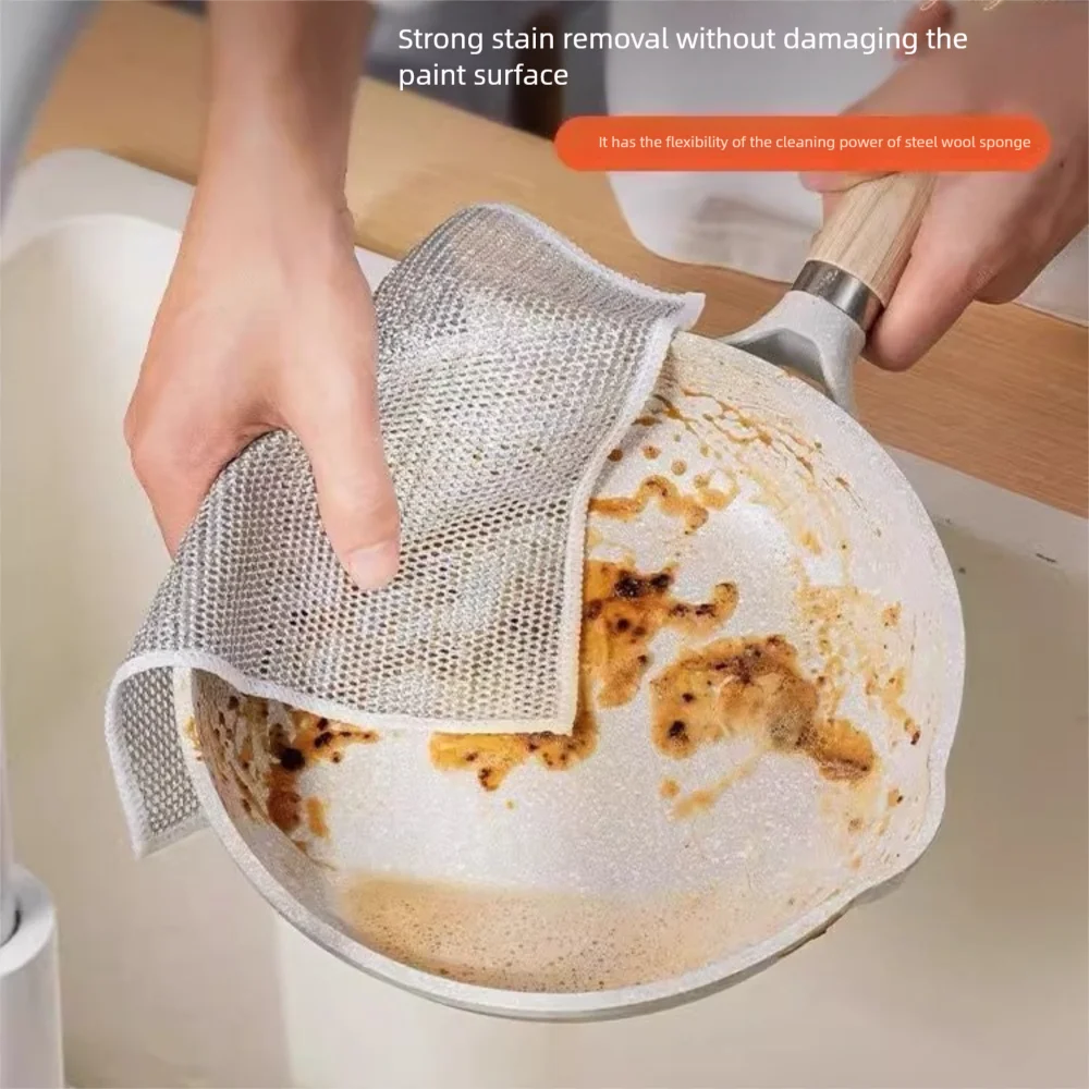 A hand is using a mesh cleaning rag to remove stains from a non-stick cooking dish.